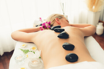 Hot stone massage at spa salon in luxury resort with day light serenity ambient, blissful woman...
