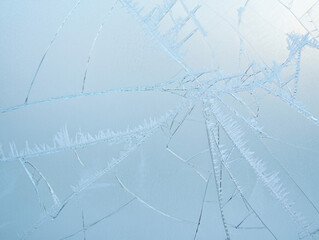Intricate patterns of ice crystals form mesmerizing fractures across a cold frosted window in winter abstract beauty