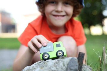 Little boy playing with toy car outdoors, selective focus