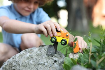 Little boy playing with toy car outdoors, selective focus