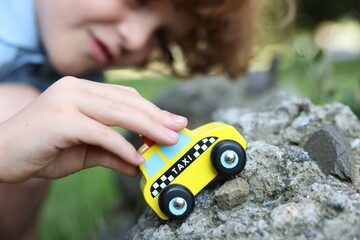 Little boy playing with toy car outdoors, selective focus