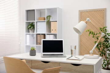 Stylish workplace with laptop and stationery on white table in office