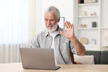 Senior man having online consultation with doctor via laptop at table indoors