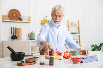Elderly man cooking at white marble table in kitchen