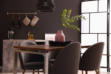 Wooden table with chairs and floral decor in dining room. Interior design