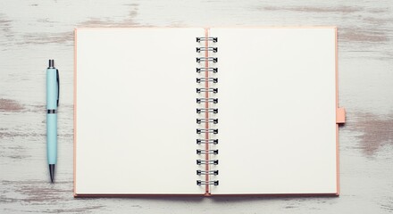 Open spiral notebook with blank pages and a light blue pen on a rustic wooden table