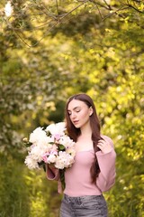 Fototapeta premium Beautiful woman with bouquet of peonies in park. Space for text