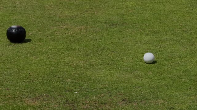 Croquet ball approaching the white ball on a grassy sports field