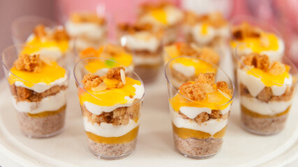Close-up of layered parfait desserts in mini cups, featuring cream, sponge cake, and fruity toppings. A vibrant and elegant treat for weddings, birthdays, and sweet tables.