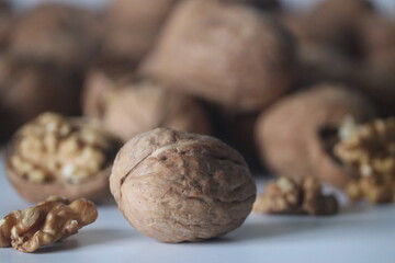 Walnuts in sharp foreground with shelled pieces blurred behind. Winter snack theme health, texture