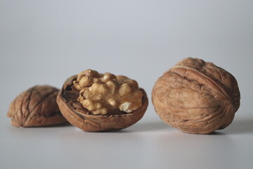 Walnuts in close up, one cracked with kernel, two whole. Winter diet, theme of texture, purity