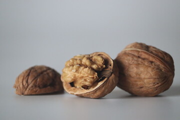 Walnuts in close up, one cracked with kernel, two whole. Winter diet, theme of texture, purity