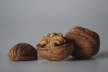 Walnuts in close up, one cracked with kernel, two whole. Winter diet, theme of texture, purity