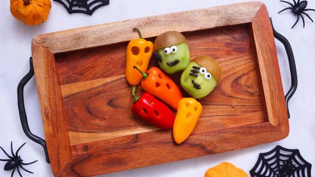 Healthy Halloween fruit and vegetable platter. Overhead view stop motion placement video. Assortment of fun, spooky treats.