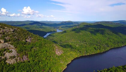 Expansive vista of a tranquil lake nestled within a range of lush green mountains.