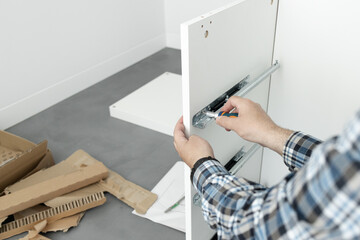 Close up of a Man Assembling a drawer slider Furniture using a screwdriver