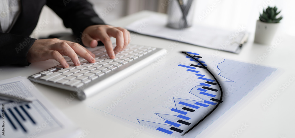 Poster a business professional focuses on financial data using a keyboard, surrounded by charts and documen