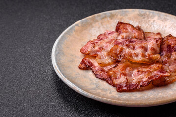 Cooked crispy fried pork bacon strips for a hearty breakfast. Fried bacon strips