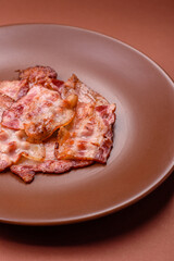 Cooked crispy fried pork bacon strips for a hearty breakfast. Fried bacon strips