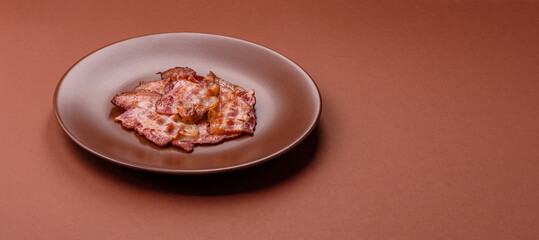 Cooked crispy fried pork bacon strips for a hearty breakfast. Fried bacon strips