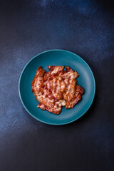 Cooked crispy fried pork bacon strips for a hearty breakfast. Fried bacon strips