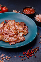 Cooked crispy fried pork bacon strips for a hearty breakfast. Fried bacon strips