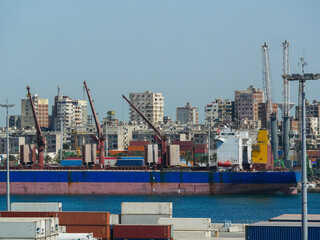 Alexandria, Egypt - 05.04.2025  Container cargo ship with loading cranes and stacked shipping...