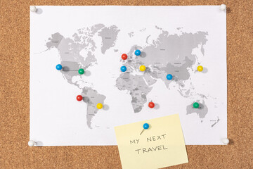 My next travel destination concept. Pushpins on world map on Corkboard and yellow sticky note