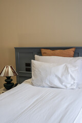 Hotel room scene with bed pillows and lamp on table,White soft pillows on bed,contemporary,Space for text.