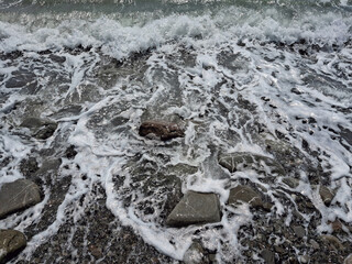 close-up view of wave foam on pebbles at the seashore