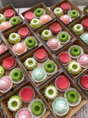 Boxes of colorful mini cakes and macarons, a sweet dessert assortment.