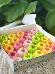 Box of colorful flower-shaped sweets, a delightful dessert assortment.