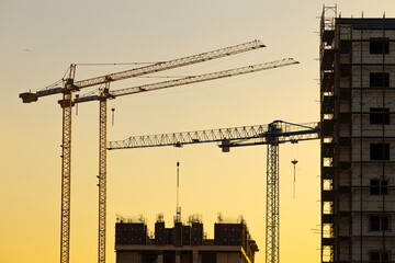 Construction of a new residential area using high-rise cranes at sunset.