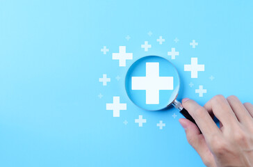 Plus sign symbol. Magnifying glass focusing on plus sign surrounded by small plus icons on blue...