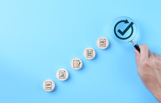 Document approval and quality assurance process concepts. Hand holding a magnifying glass focusing on check mark symbol with document icon, document approval, compliance, and quality assurance process