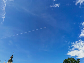 Cirrus clouds and long airplane trail row. Aero plane contrail in blue cloudy sky background. Horizontal line track from flying fast aeroplane in distance