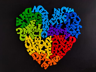 Alphabet letters are arranged in a heart shape on a black background. 