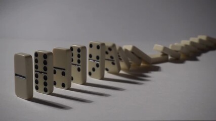 Falling dominoes in slow motion. Close-up of the domino effect. Chain reaction concept.