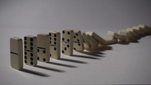 Falling dominoes in slow motion. Close-up of the domino effect. Chain reaction concept.
