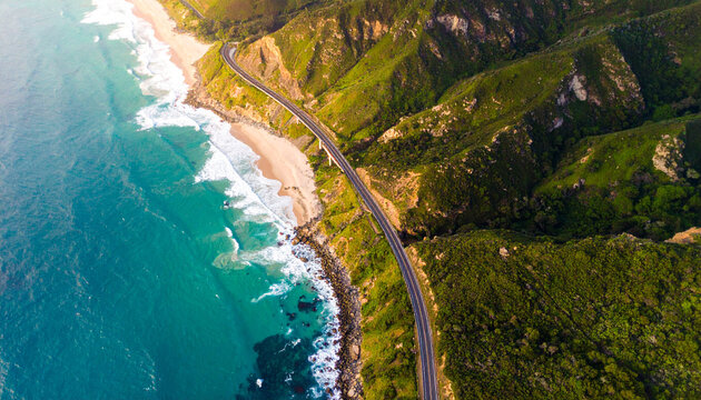 Scenic Aerial View of Coastal Road Along Ocean and Green Cliffs