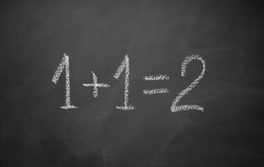 One plus one equals two hand written on chalkboard. Math simple equation