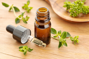 Oregano essential oil and fresh oregano on wooden table. Origanum vulgare oil