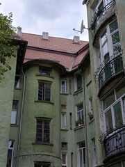 Old German residential building with green facade, balconies and tiled roof, historic architecture close-up in Kaliningrad, Russia.