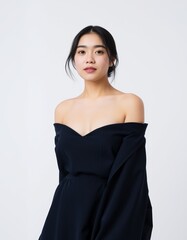 Portrait of a young asian woman with dark hair wearing an off the shoulder black dress