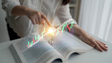 A woman engages with an open book displaying financial charts, representing investment education...