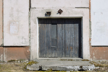Wooden door in a concrete wall of a building. Locked black door. Closed entrance to a city house.