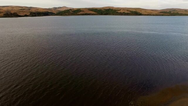 Serene lake landscape with rolling hills under a cloudy sky offering peaceful scenery