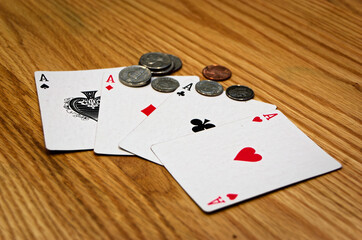 Ace Cards Fanned With Mixed Coins On Wooden Surface - Poker Night Gambling Scene