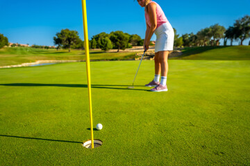 Obraz premium Female golfer putting on a sunny day