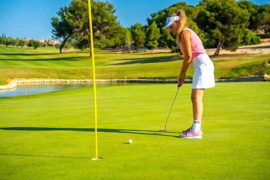 Female golfer putting on the green on a sunny day